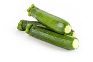 three baby green zucchinis on white background
